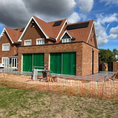 Modern Brick House Under Construction with Green Covered Openings and Solar Panels